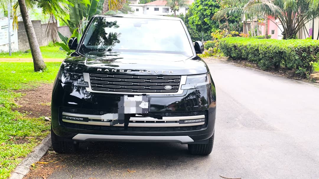 Range Rover haut de gamme: 70.000F CFA Véhicule noir garé sur un chemin bordé d'arbres.