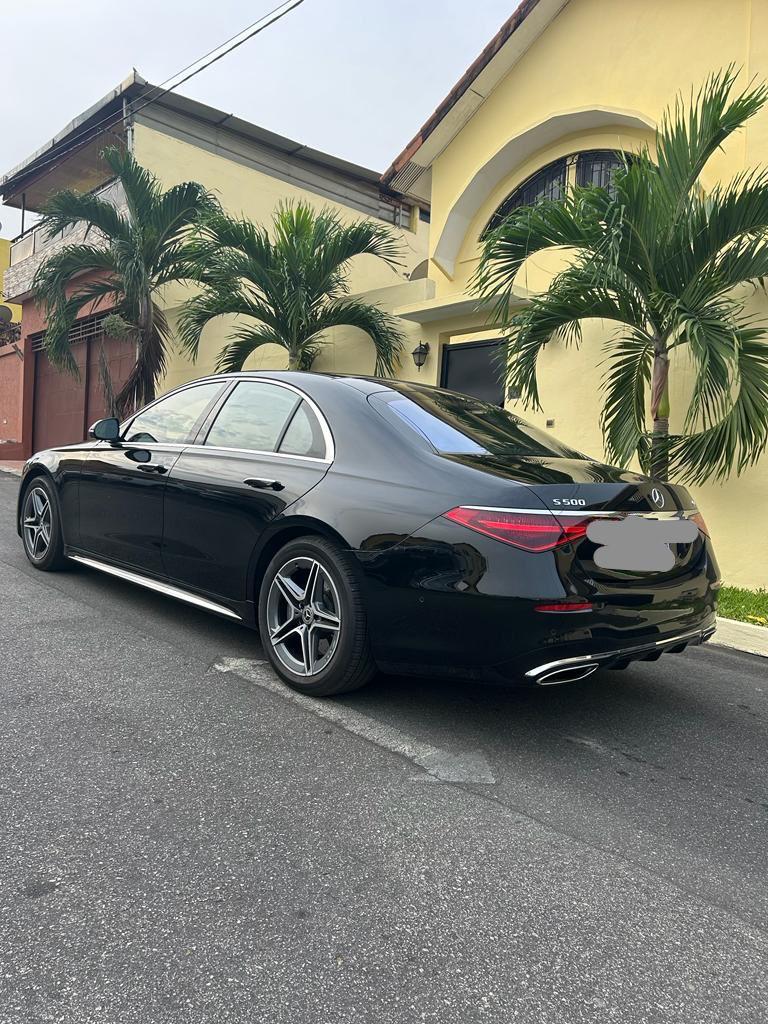 Mercedes Class S: 700.000F CFA Voiture noire garée devant un bâtiment avec des palmiers en arrière-plan.